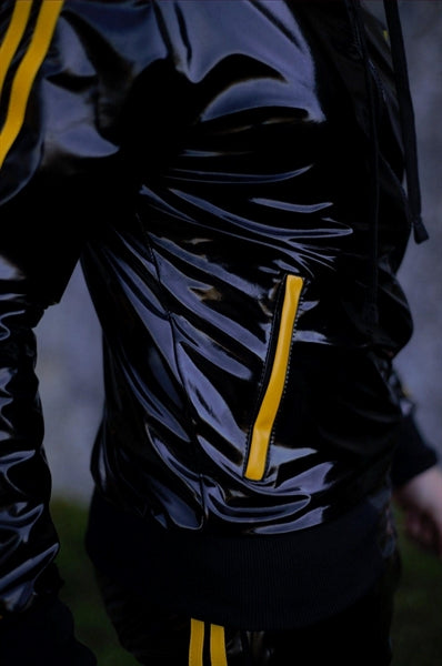 MR Riegillio PVC Tracksuit jacke mit gelben streifen von einem jungen gay getragen in schwarz glänzend mit von der seite in nahaufnahme