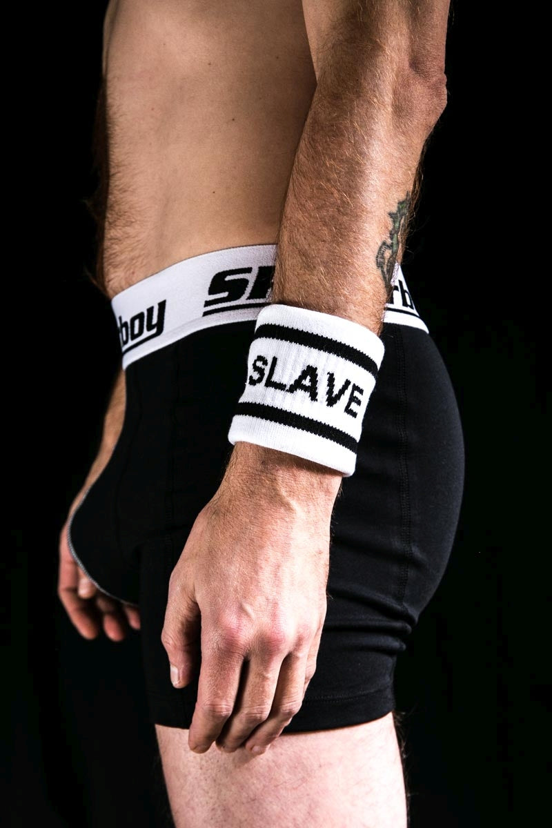 gay im dunkeln mit schwarzer sk8erboy boxershort und schweissband am linken arm mit aufschrift SLAVE von sk8erboy socken shop pride regenbogen lgbt