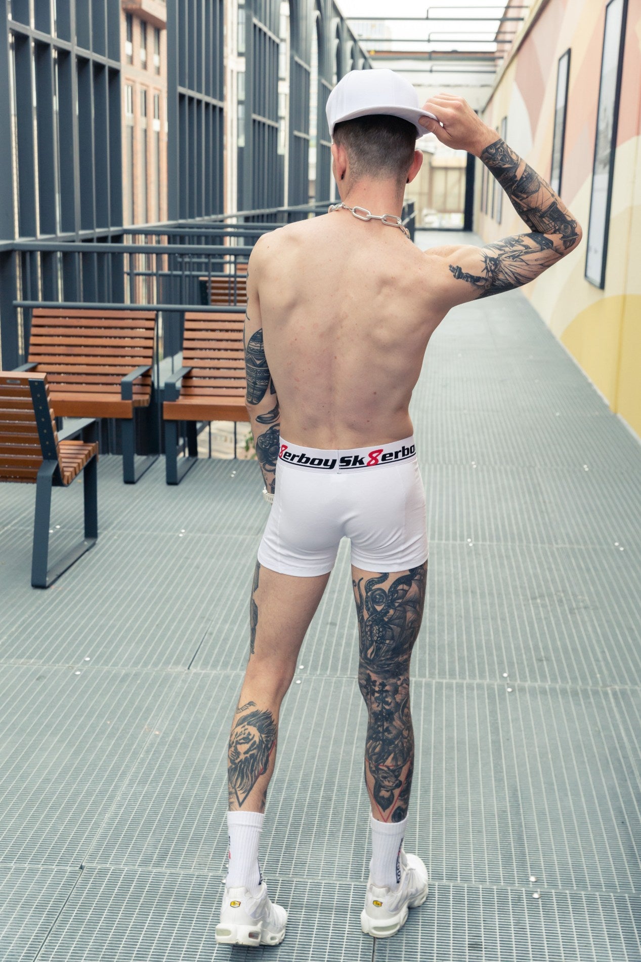 sportlicher junge von hinten mit freiem oberkörper trägt eine weisse boxershort von sk8erboy mit logo auf dem bund und passenden crew socks in weissen nike tn turnschuhen mit kappe